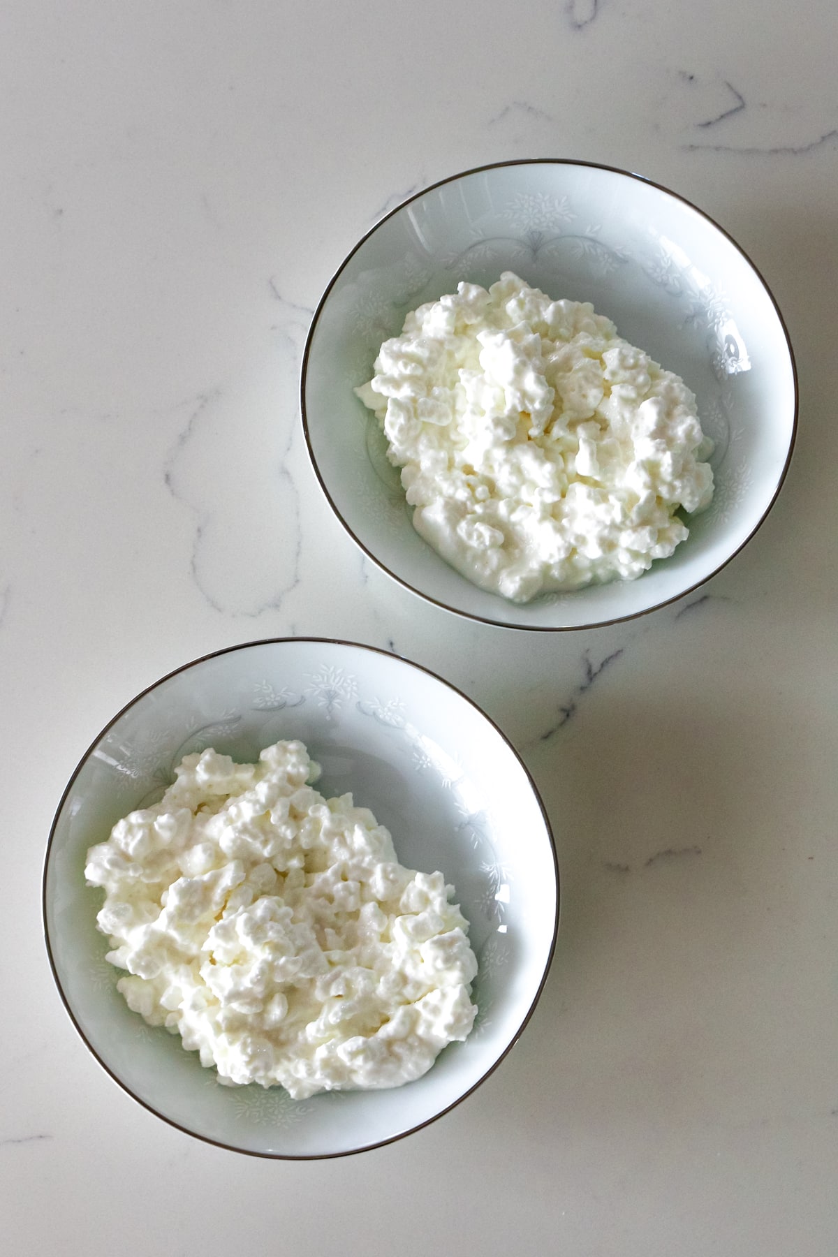 two small bowls full of large curd unblended cottage cheese.