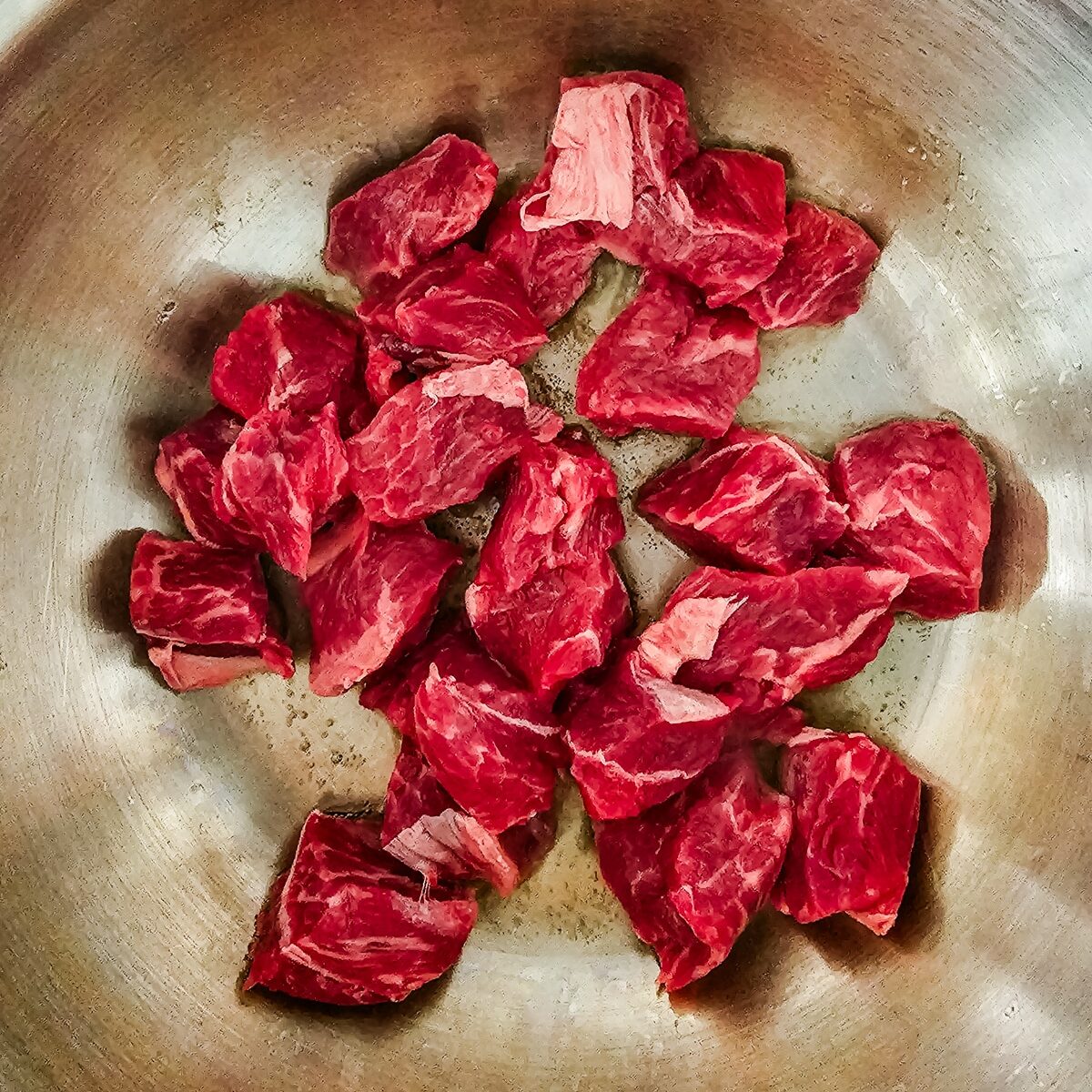 beef stew is cooked in a stainless steel pot.