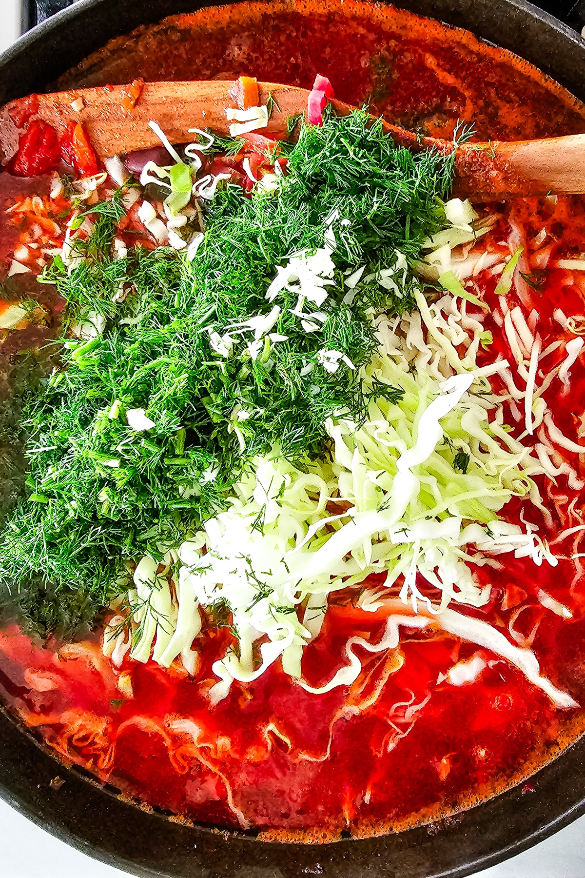 finely shredded cabbage and chopped dill in a large pot of beet soup.