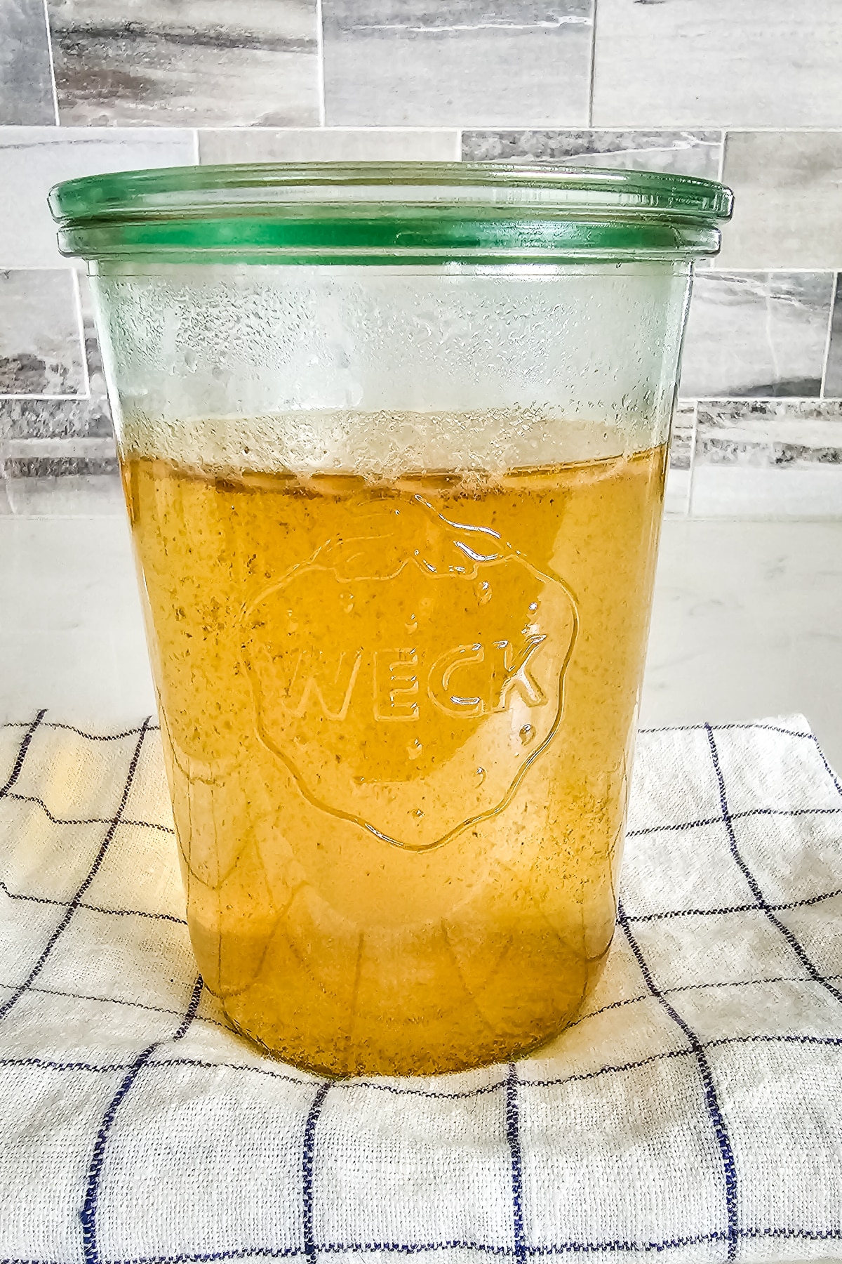 meat broth in a weck jar with a towel underneath.