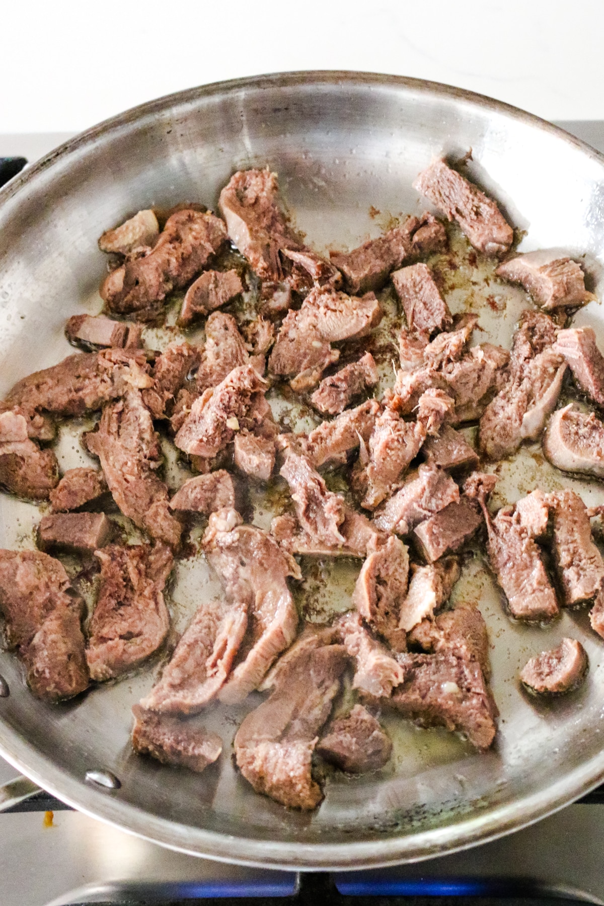 Beef tongue searing on a pan with butter.
