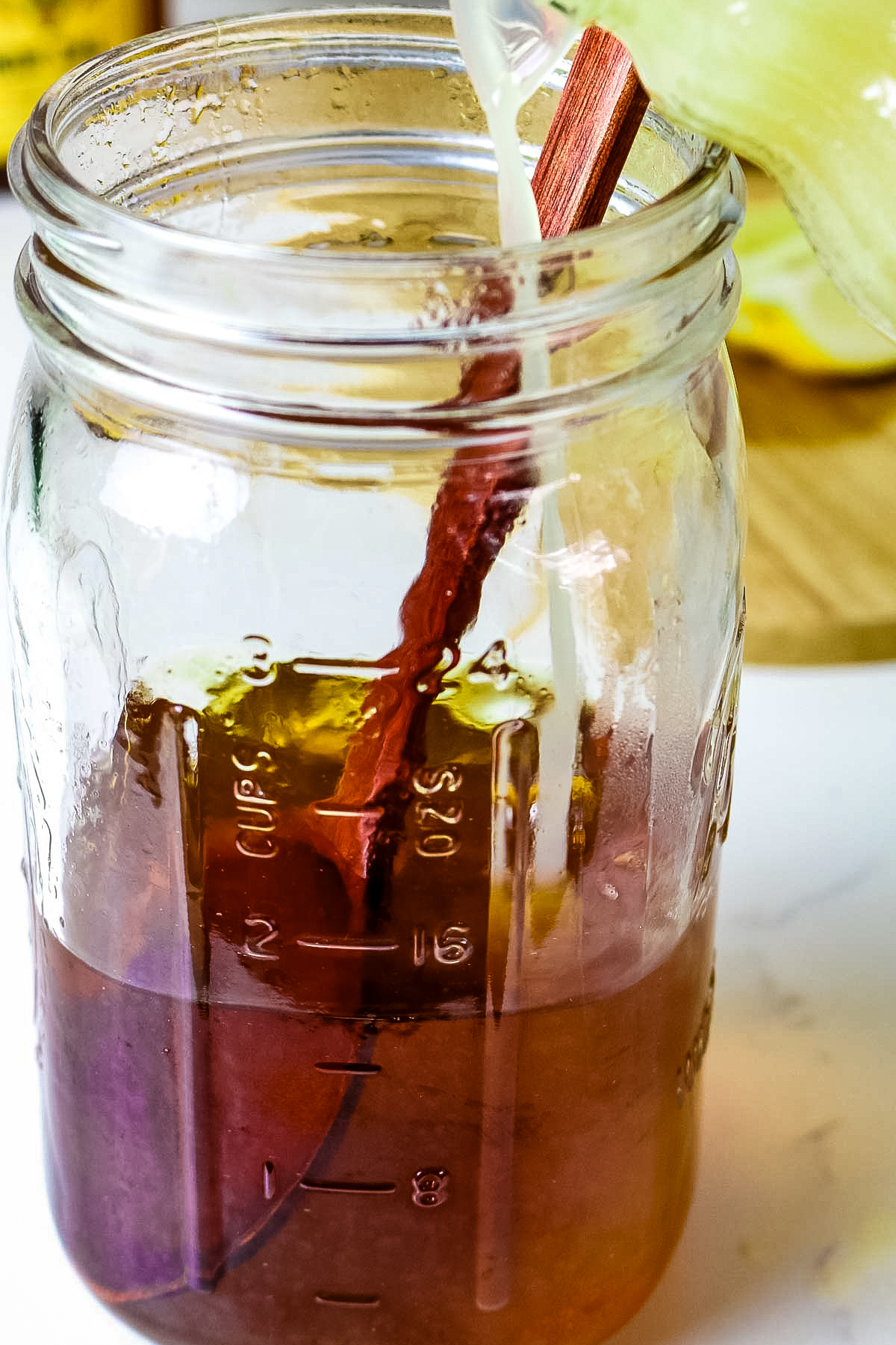 honey juice is added to brewed herbal tea in a mason jar.