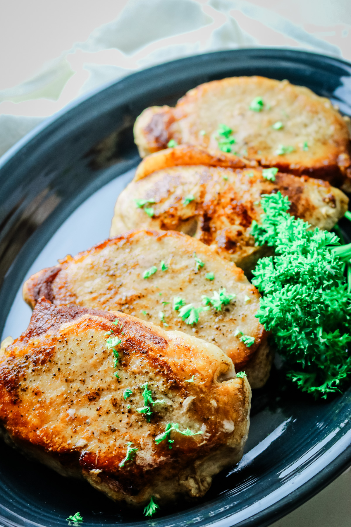 seared pork chops on a platter with parsley on the right of the platter.