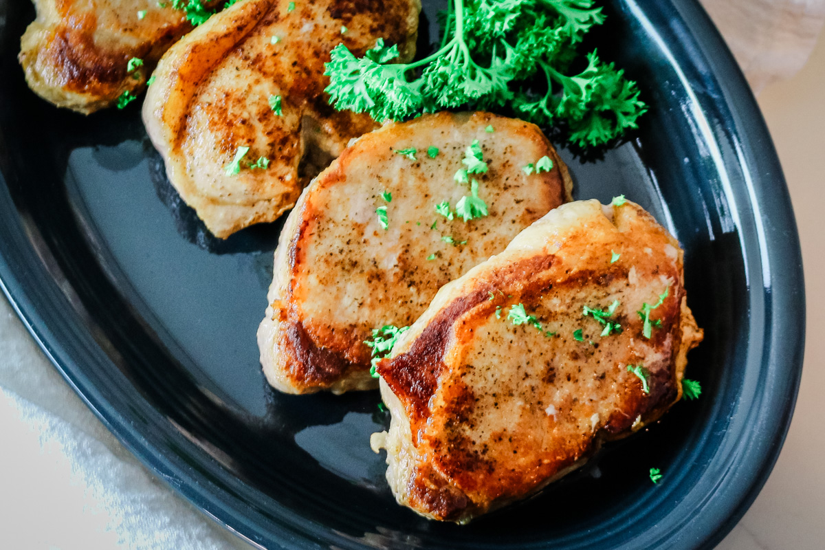 Pork chops on a platter with parsley garnish.