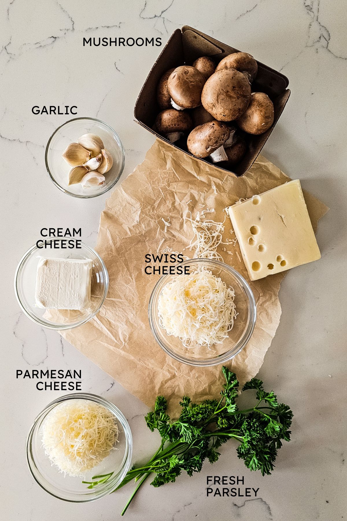 overlay of ingredients for stuffed mushrooms with mushrooms, cheeses, garlic, and fresh parsley.