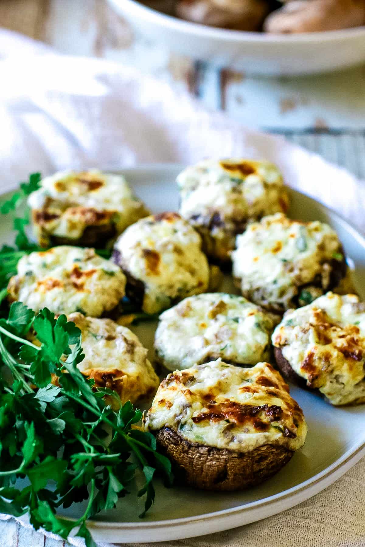 stuffed mushrooms on a platter with fresh parsley.