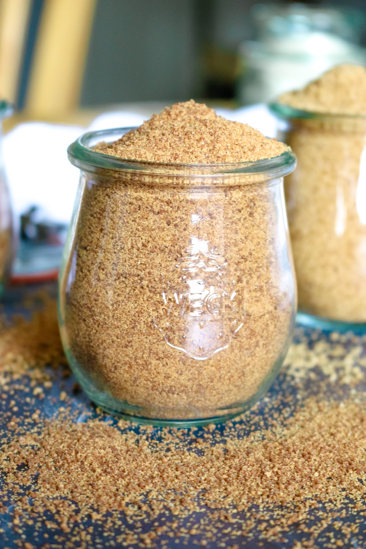 coconut sugar in a glass jar with some loosely sprinkled in the front.
