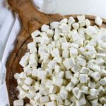 homemade marshmallows cut into bite-size pieces on a circular wooden cutting board.