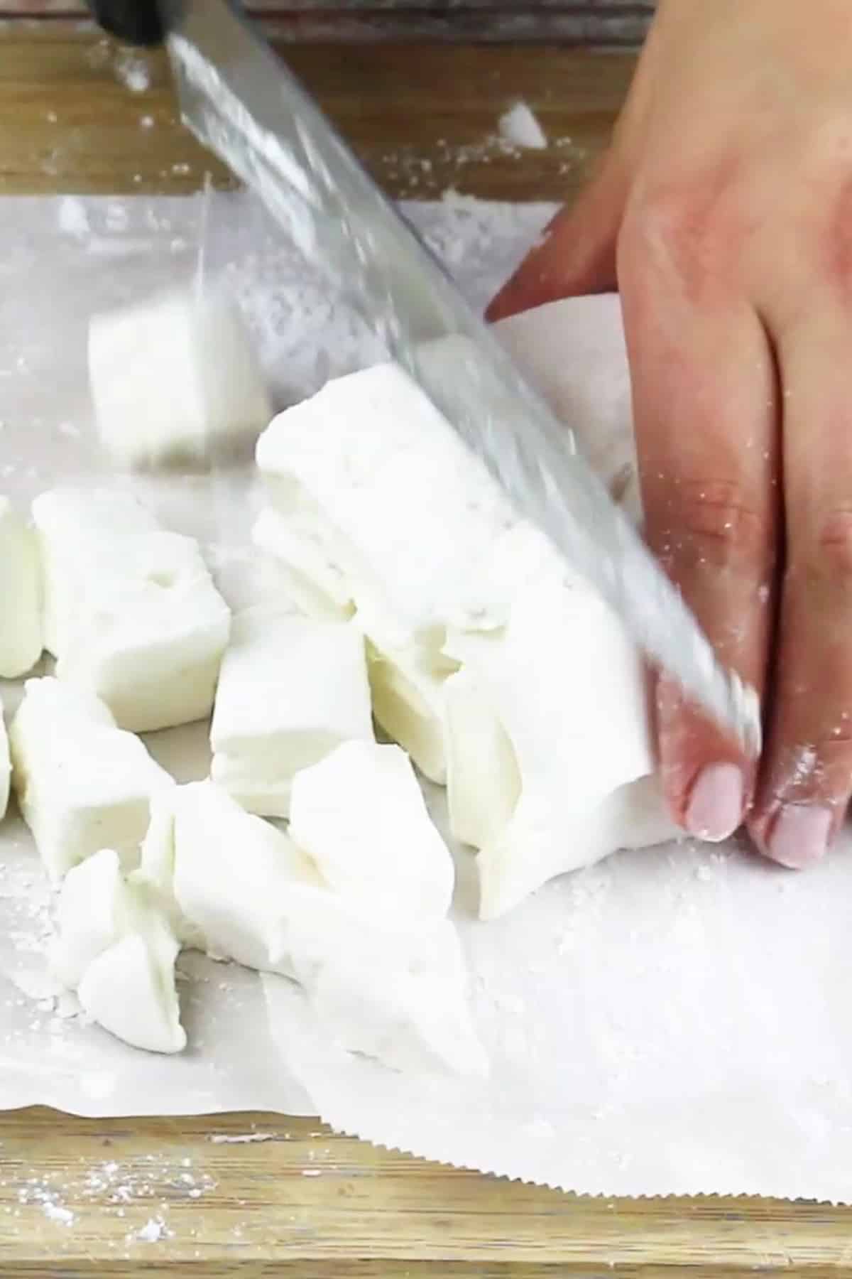 homemade marshmallows cut into small pieces with a chef's knife.