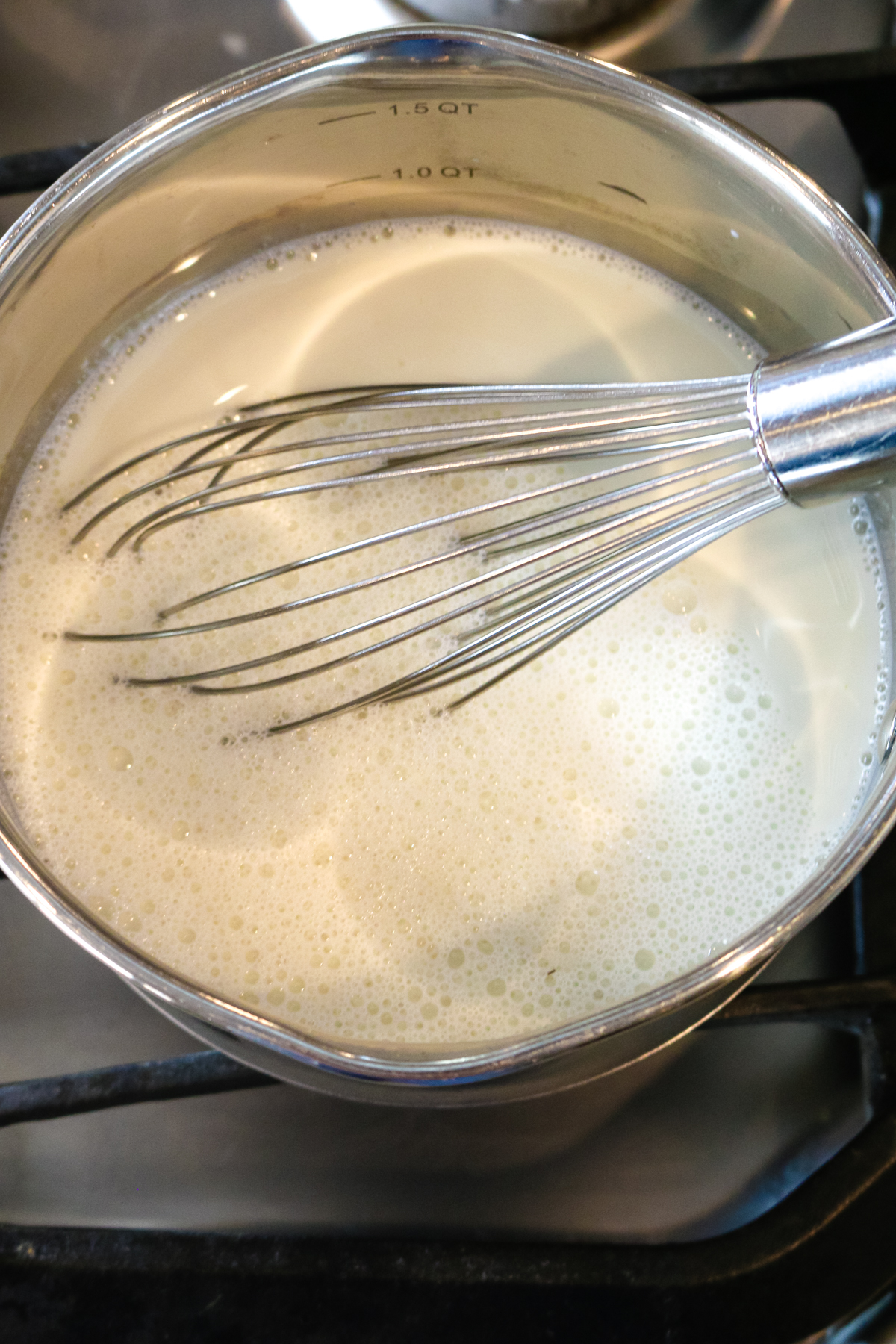a whisk inside of a metal pan mixing milk.