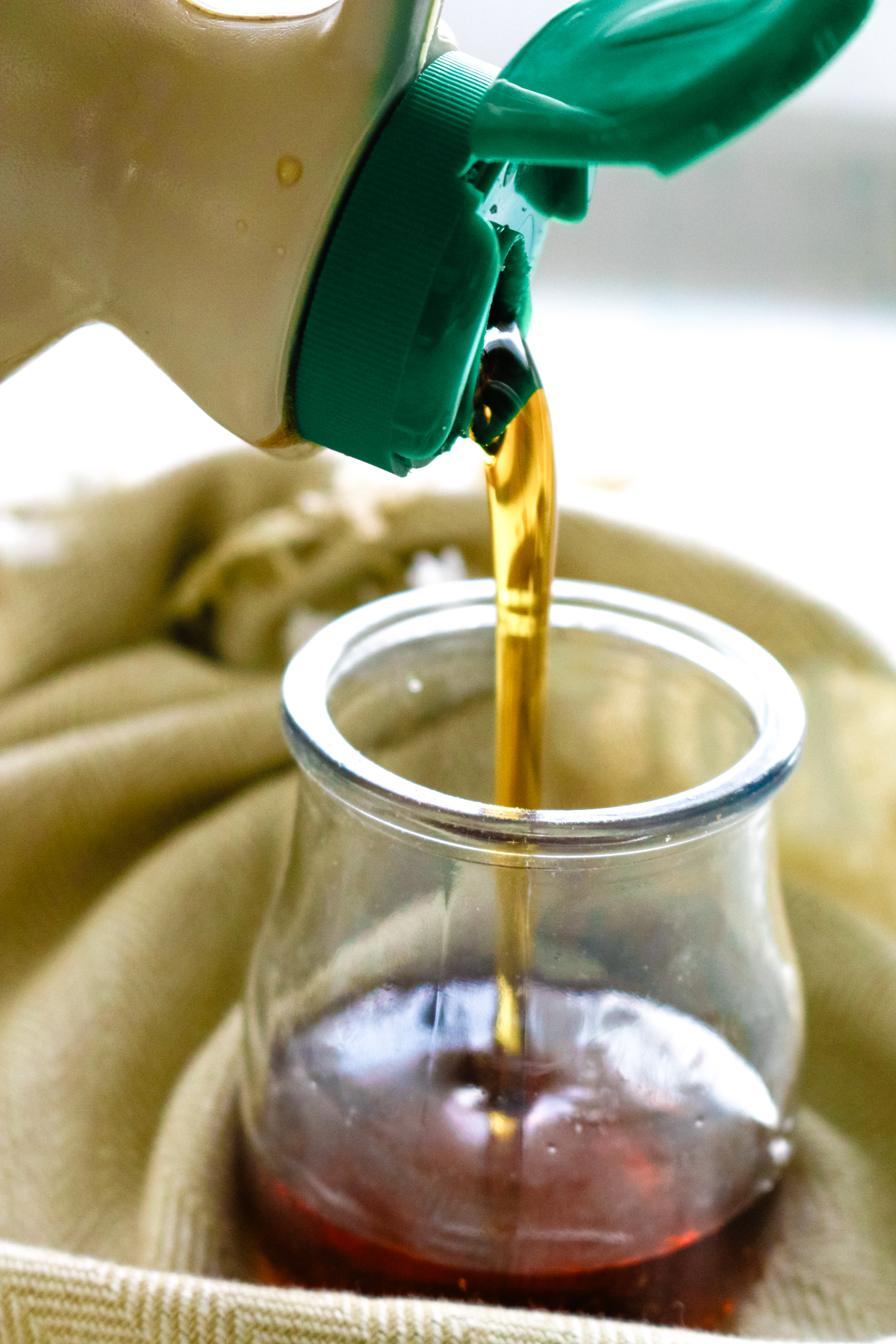 maple syrup being poured into a small glass jar.