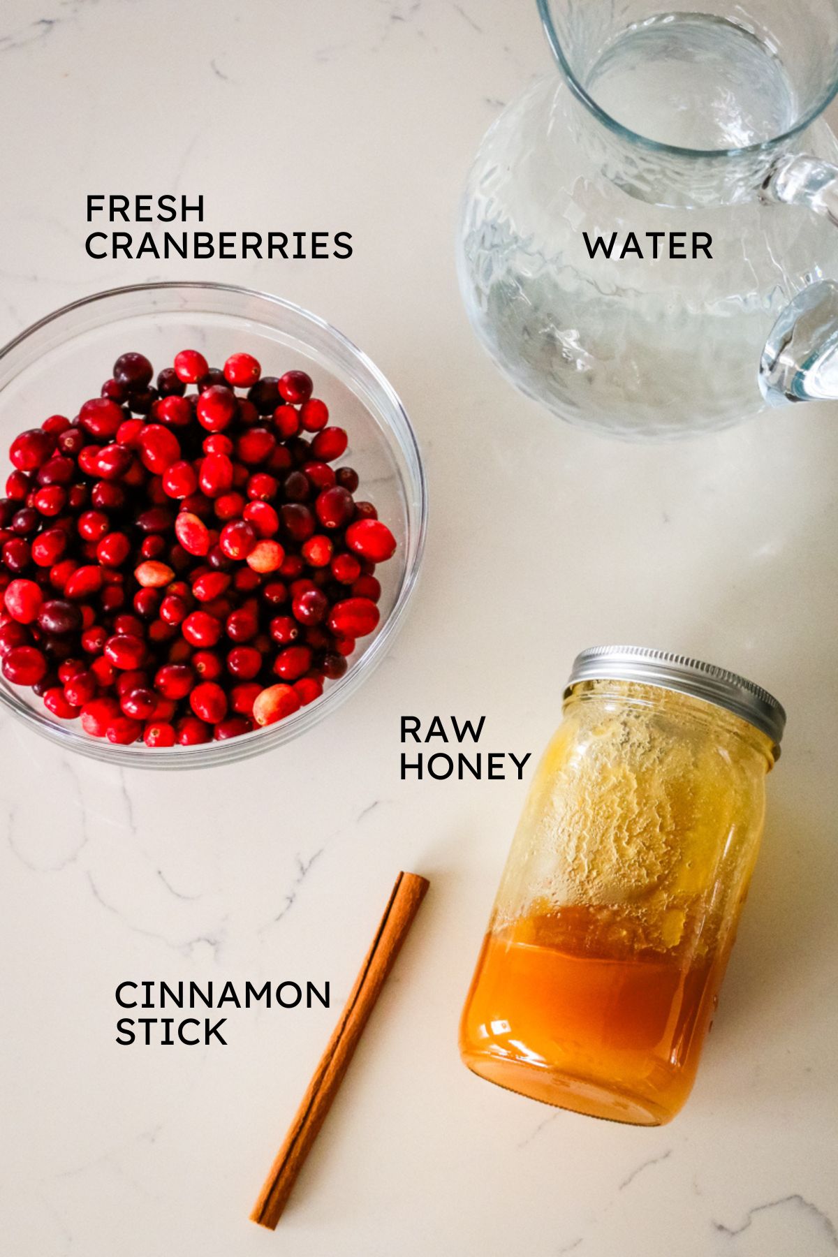 ingredients layed out including fresh cranberries, water, raw honey, and cinnamon stick