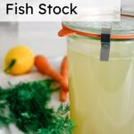 fish stock in glass jar sitting on a towel with dill, lemons, and carrots on the left of it with text overlay saying how to make fish stock