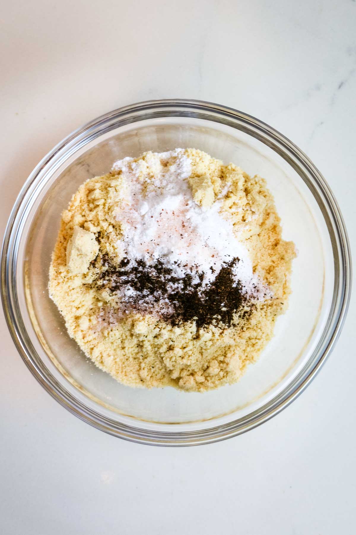 ingredients to make oatmeal bars in a glass bowl on a white counter