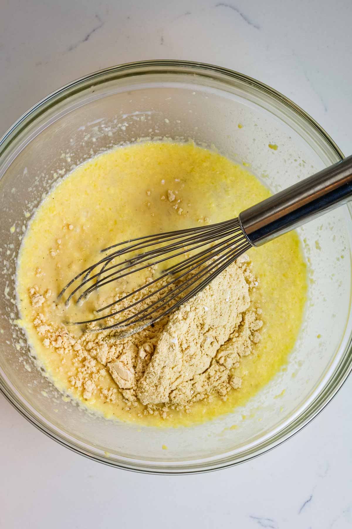 metal whisk in a bowl of butter and other ingredients to make oatmeal bars