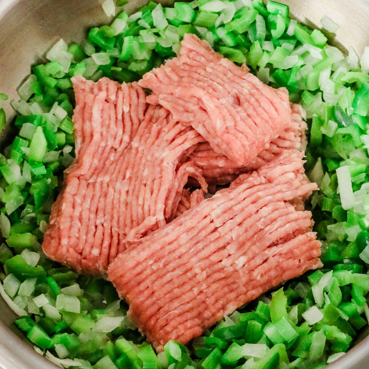 a pot with softened bell peppers and onions and ground turkey in center.