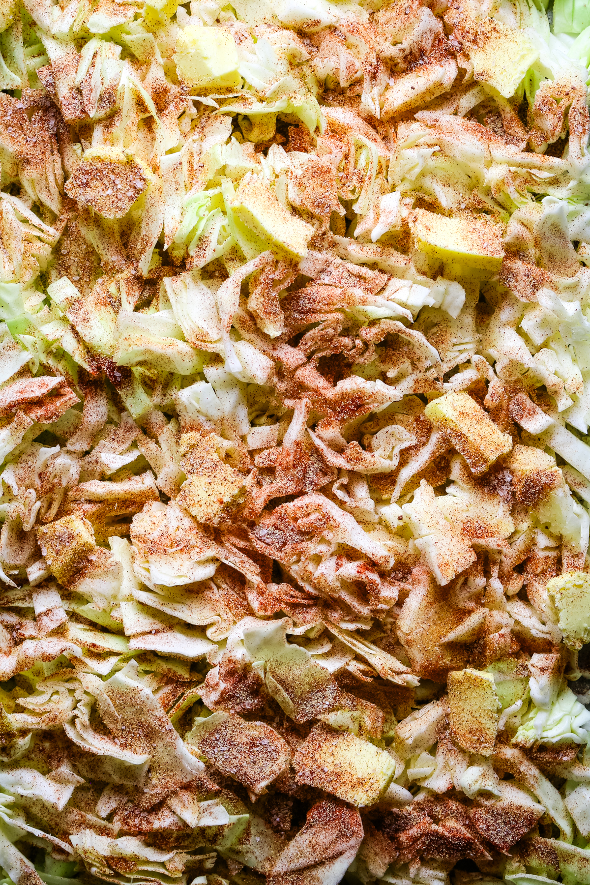 seasoned sliced cabbage on a sheet pan with paprika, butter, and garlic powder.