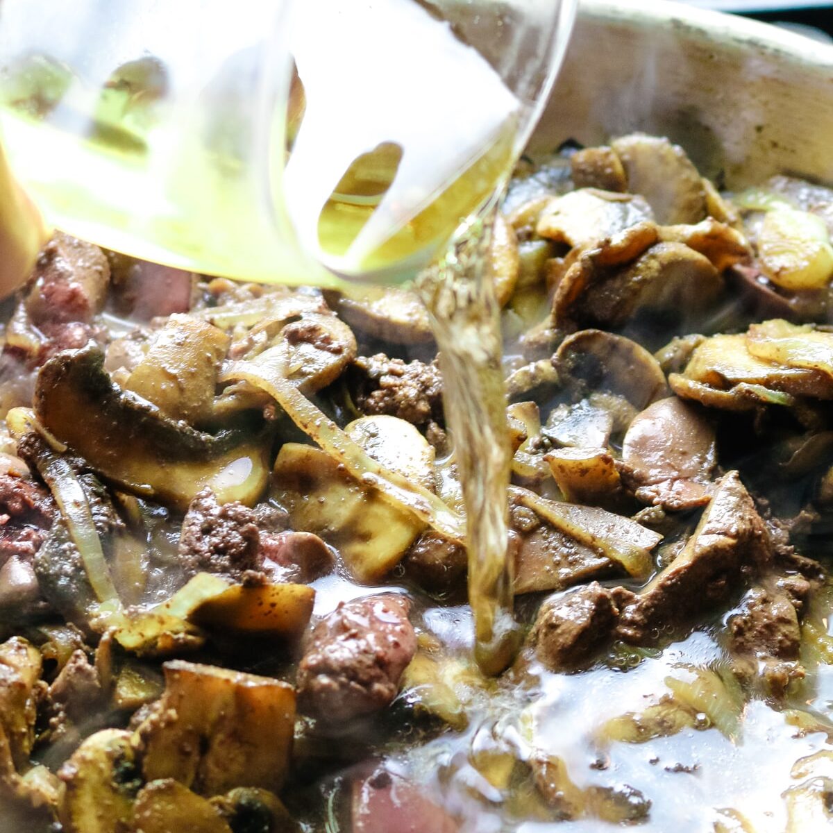 white wine poured into the skillet with mushrooms and livers.