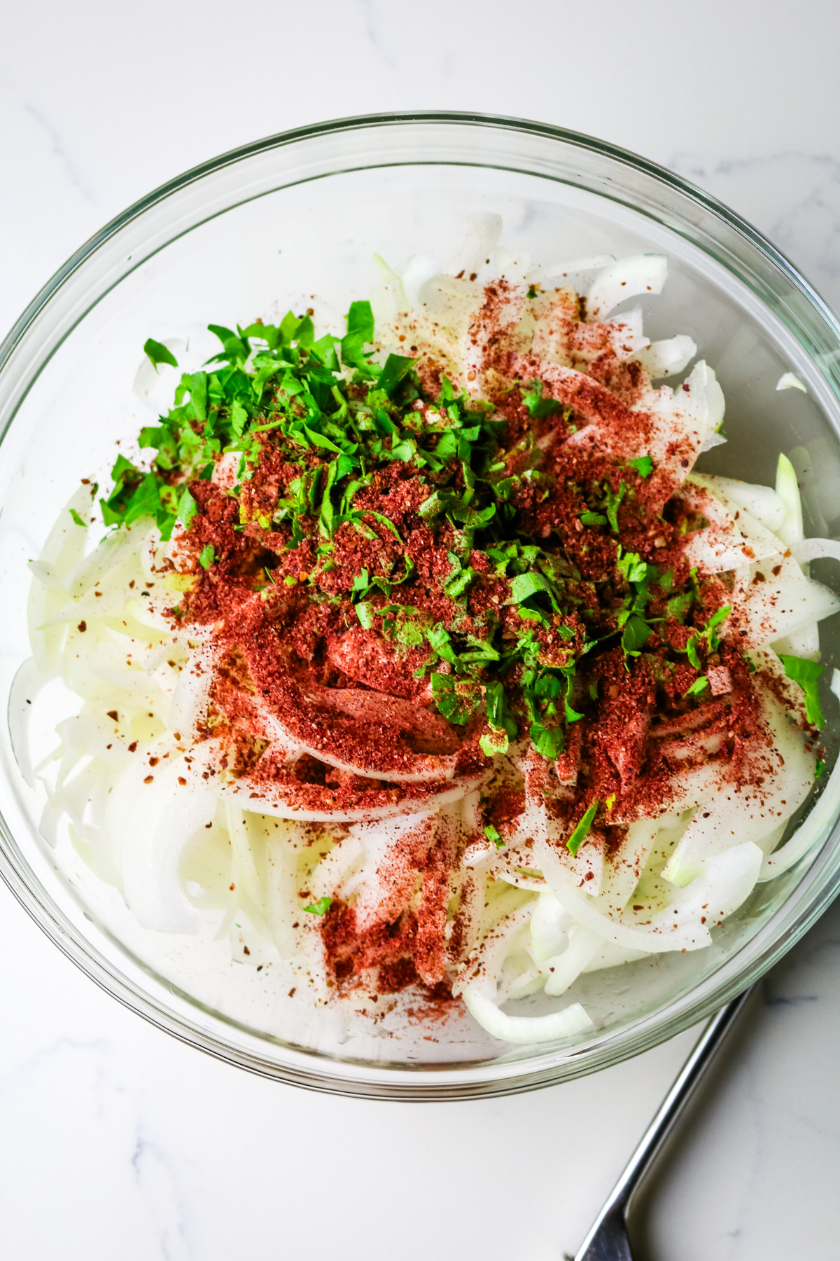 thinly sliced yellow onion with sumac seasoning and fresh parsley on top.