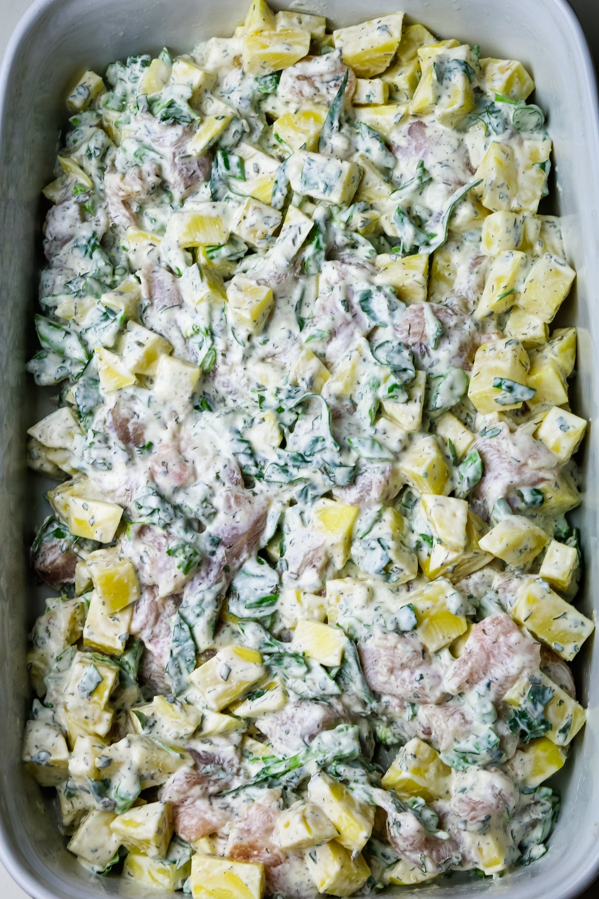 chicken potato casserole uncooked and unbaked in a white baking dish.