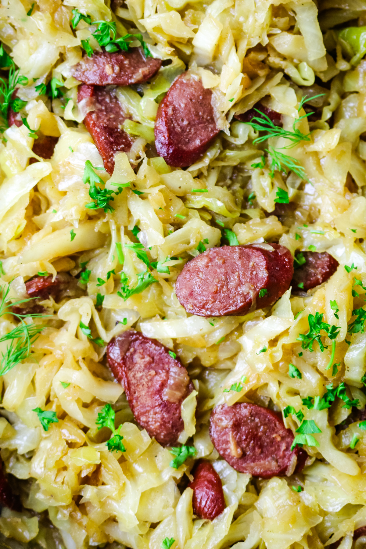 close up of sliced cabbage with polish sausage rounds.