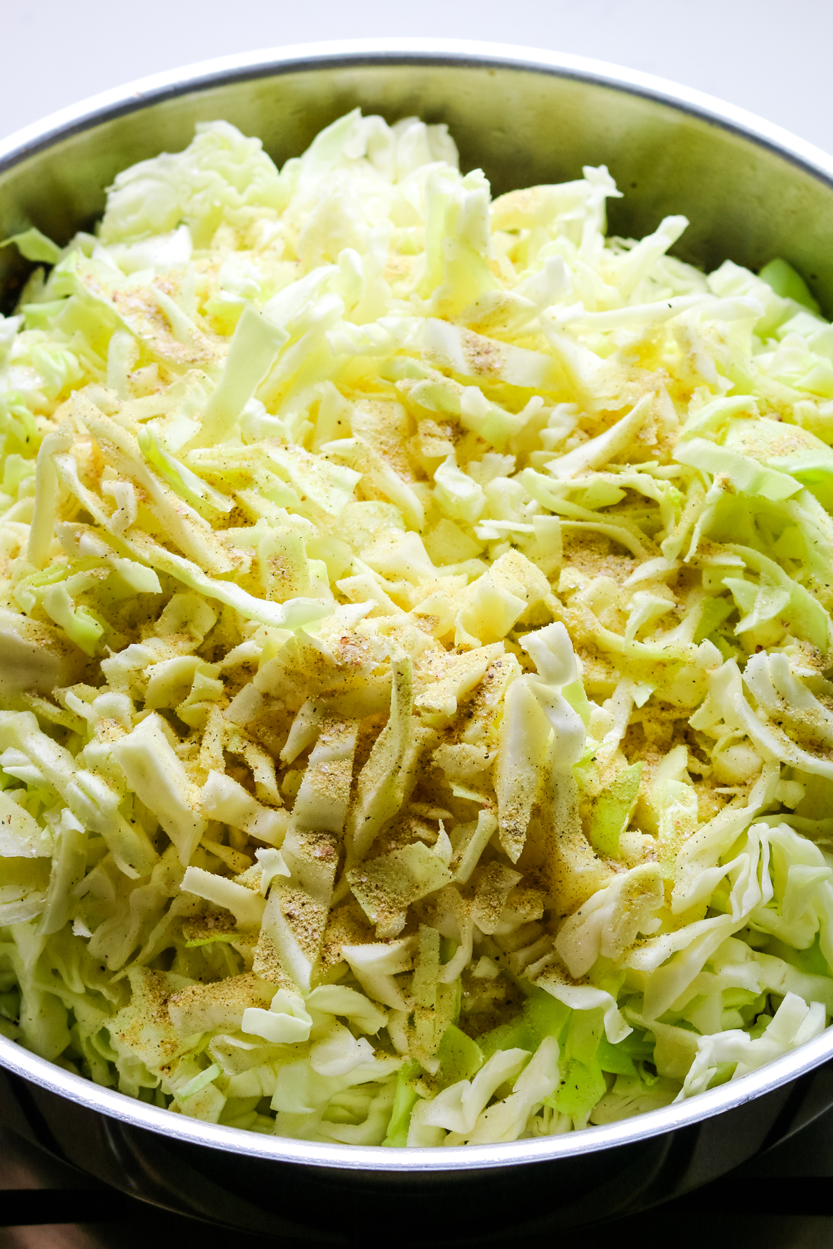 sliced cabbage with seasonings in a large pan.