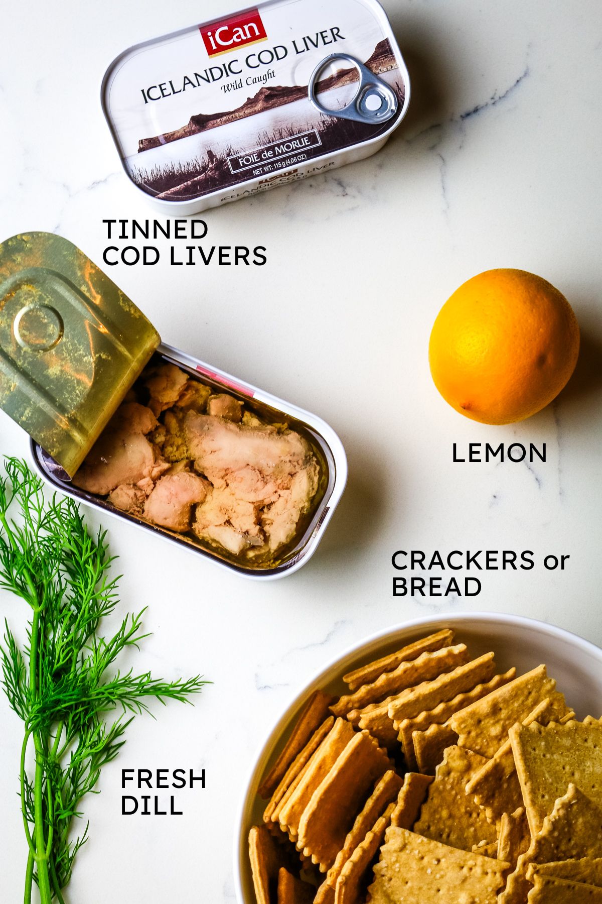ingredients for cod liver pate including tinned cod livers, lemon, crackers, and dill.