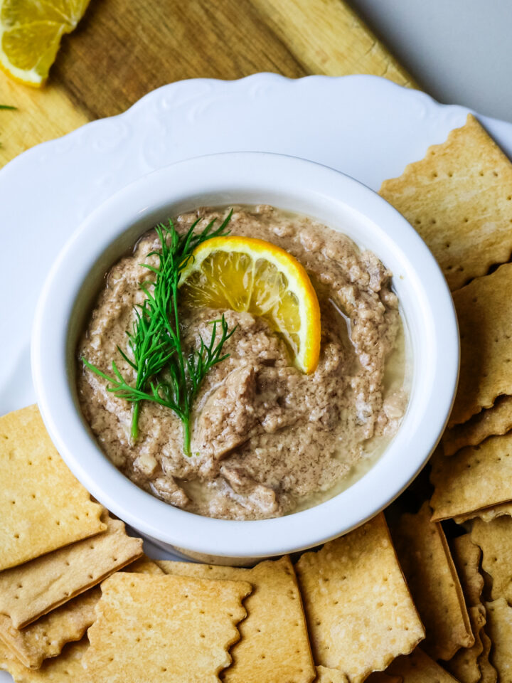 cod liver pate in a white ramekin with crackers on the side.