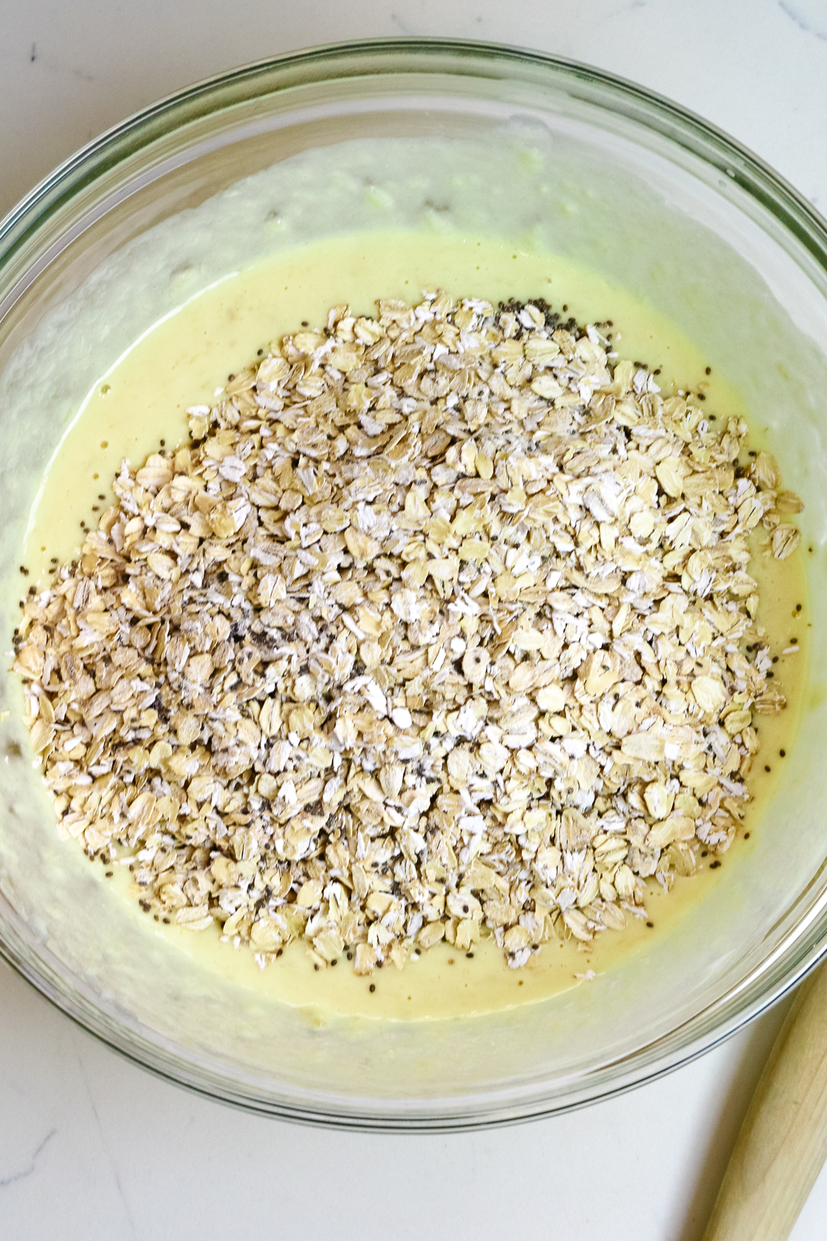 dry baked protein oats ingredients on top of wet ingredients in a large mixing bowl.