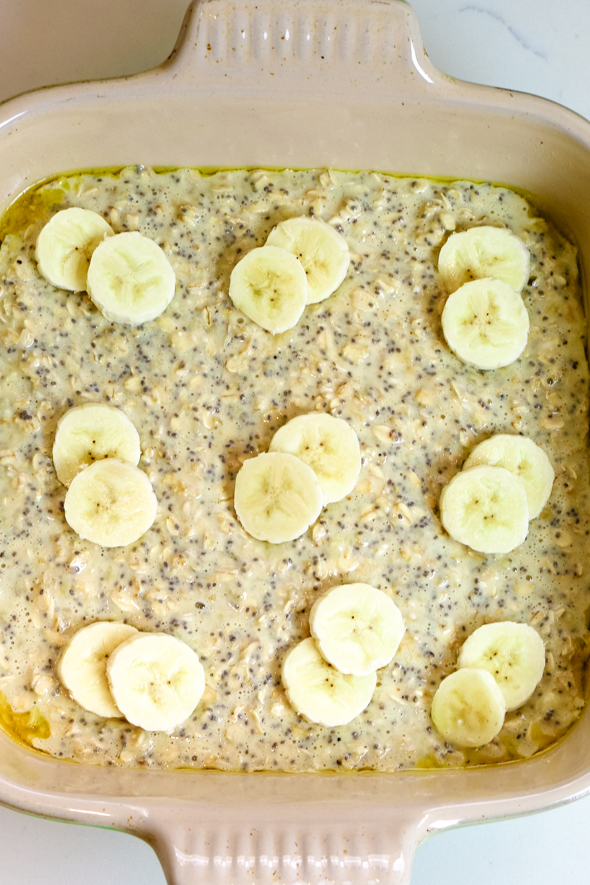 protein oats with chia seeds and sliced bananas on top in a baking dish.