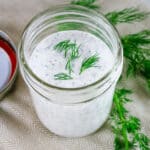 ranch dressing in a mason jar with fresh dill on top.
