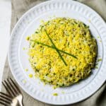 cod liver salad with eggs on a white plate with two forks in the bottom left corner.