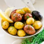 potato medley in a white bowl with lemon wedges on the side and fresh dill.