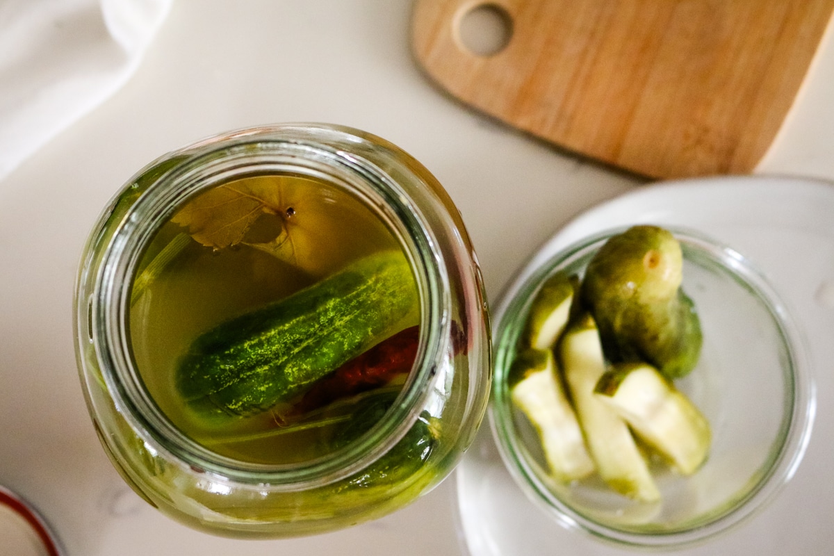 overhead of jar of pickles and cutting board to the side.