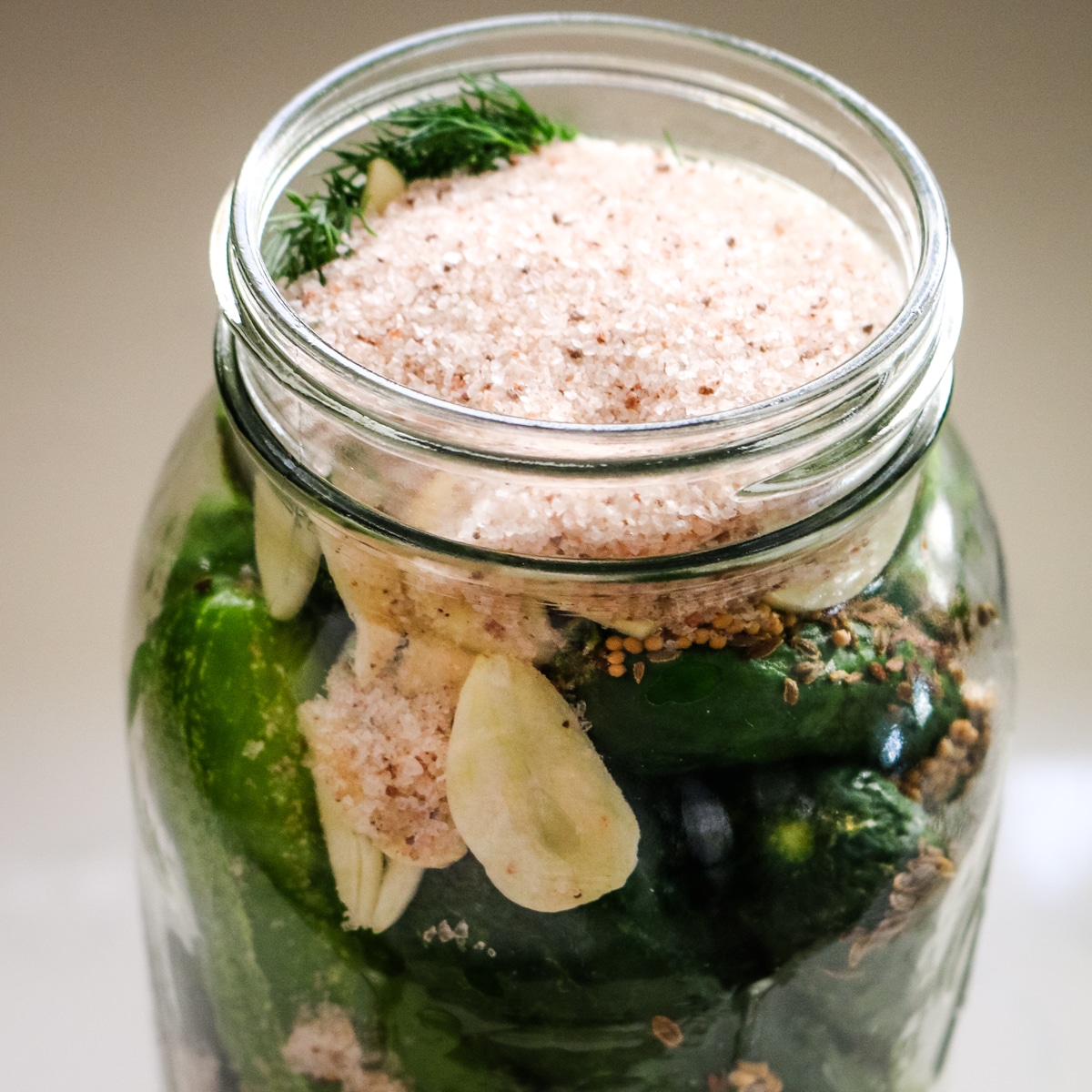 salt added to the cucumbers in a mason jar.