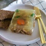 A plate of aspic with a slice of rye bread and forks.