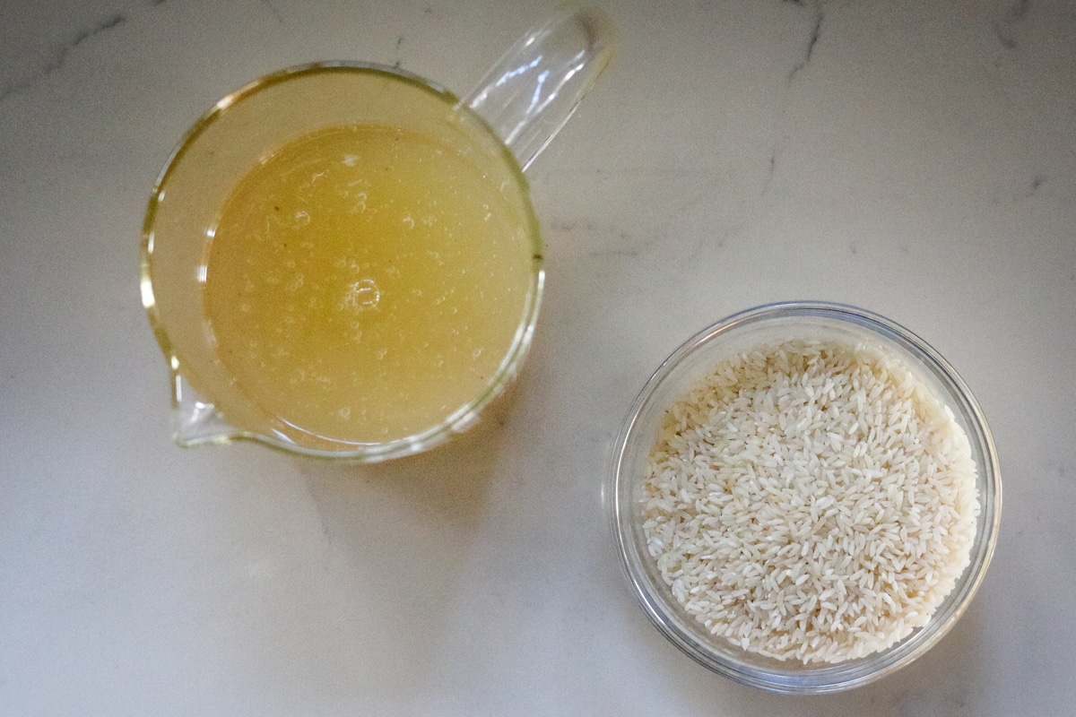 Bone broth is in a pitcher, and rice is in a clear bowl.