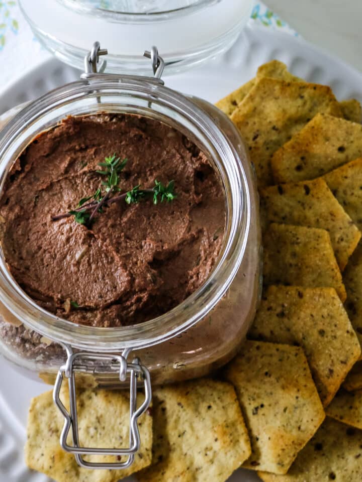 Chicken live pate on a glass jar with crackers on the side.