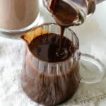 Pouring chocolate syrup into a clear jar.