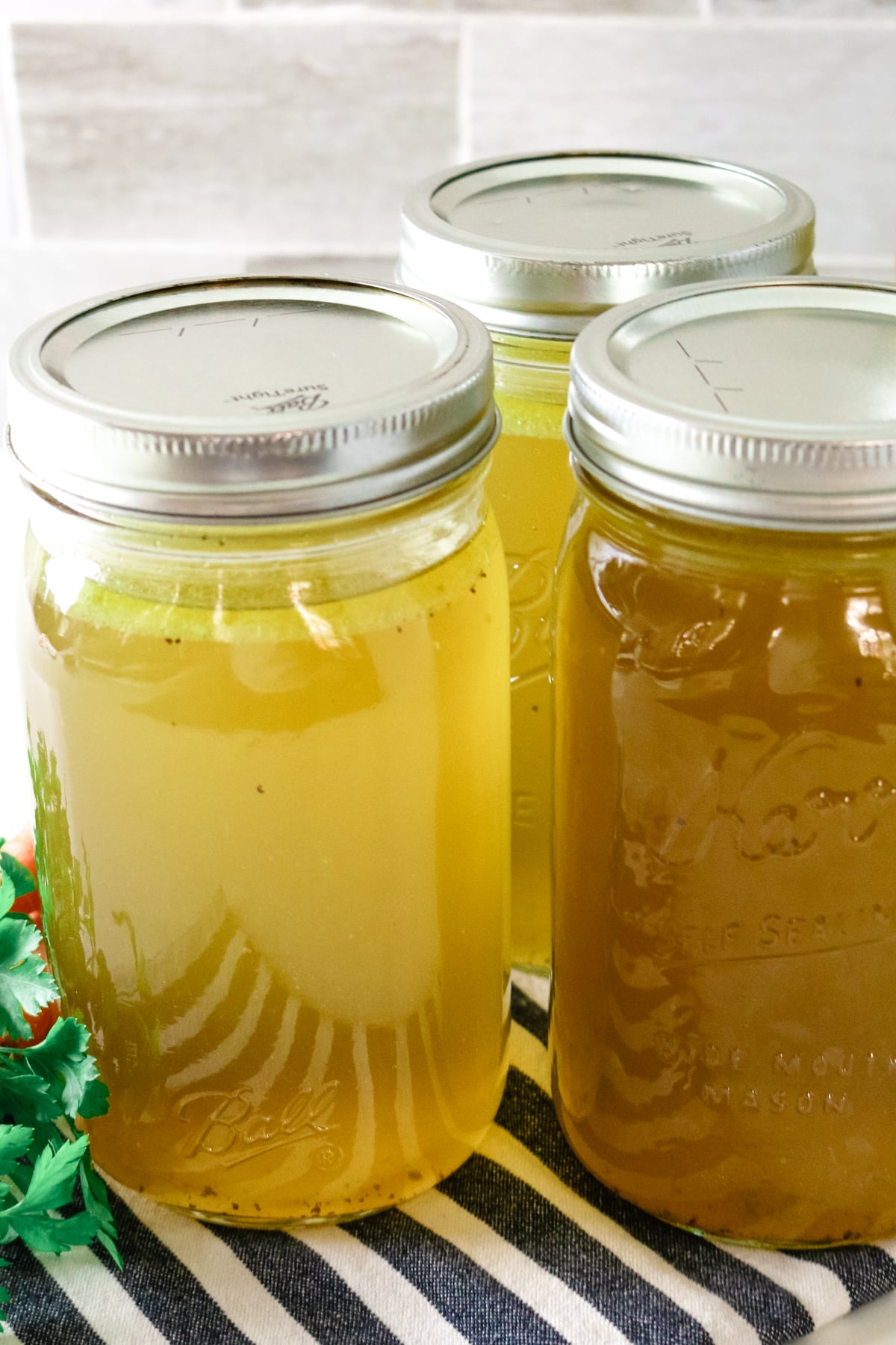Three clear jars of chicken broth.