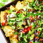 Sheet pan nachos with ground pork and vegetables on a tray.