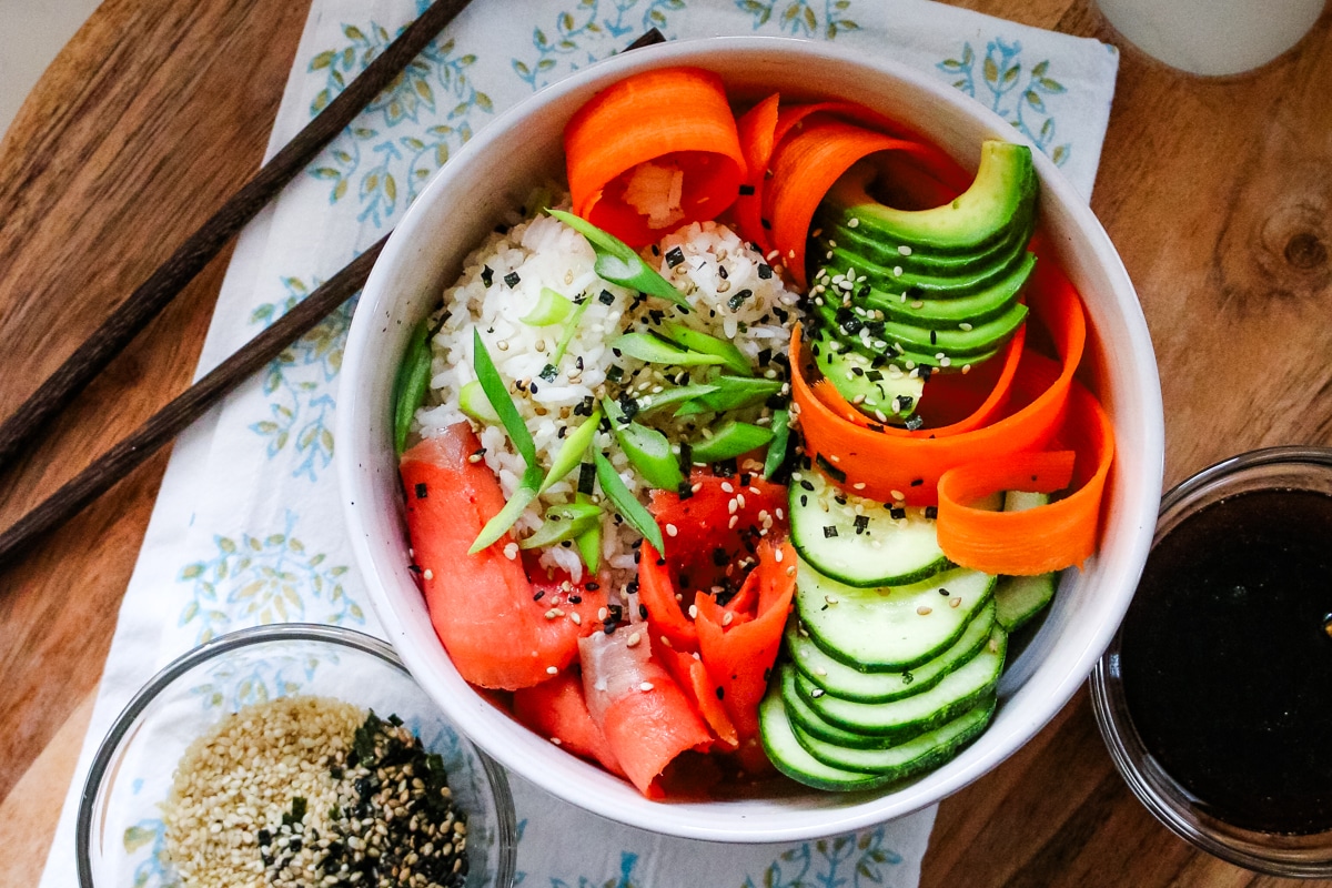 Smoked salmon in a white bowl, served with sesame seeds and soy sauce on the side.