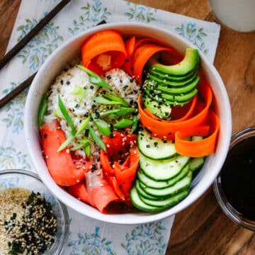 Smoked salmon in a white bowl, served with sesame seeds and soy sauce on the side.