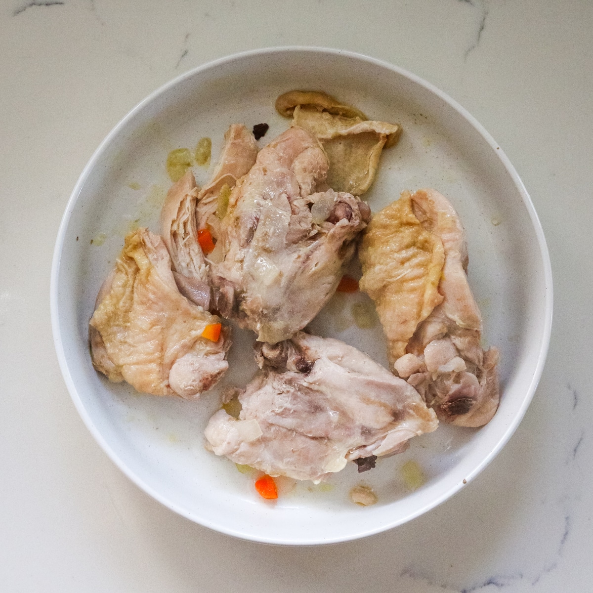 cooked chicken thighs in a white bowl.