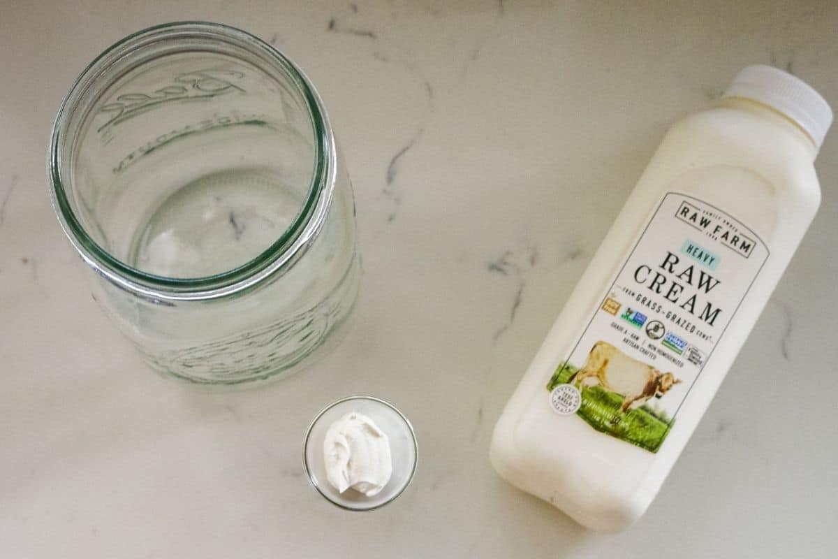 Glass jar, raw cream, and a staple on top of the table."