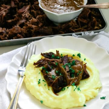 Braised beef chuck roast with mashed potatoes on a plate, and braised beef chuck in a baking tray with sauce.