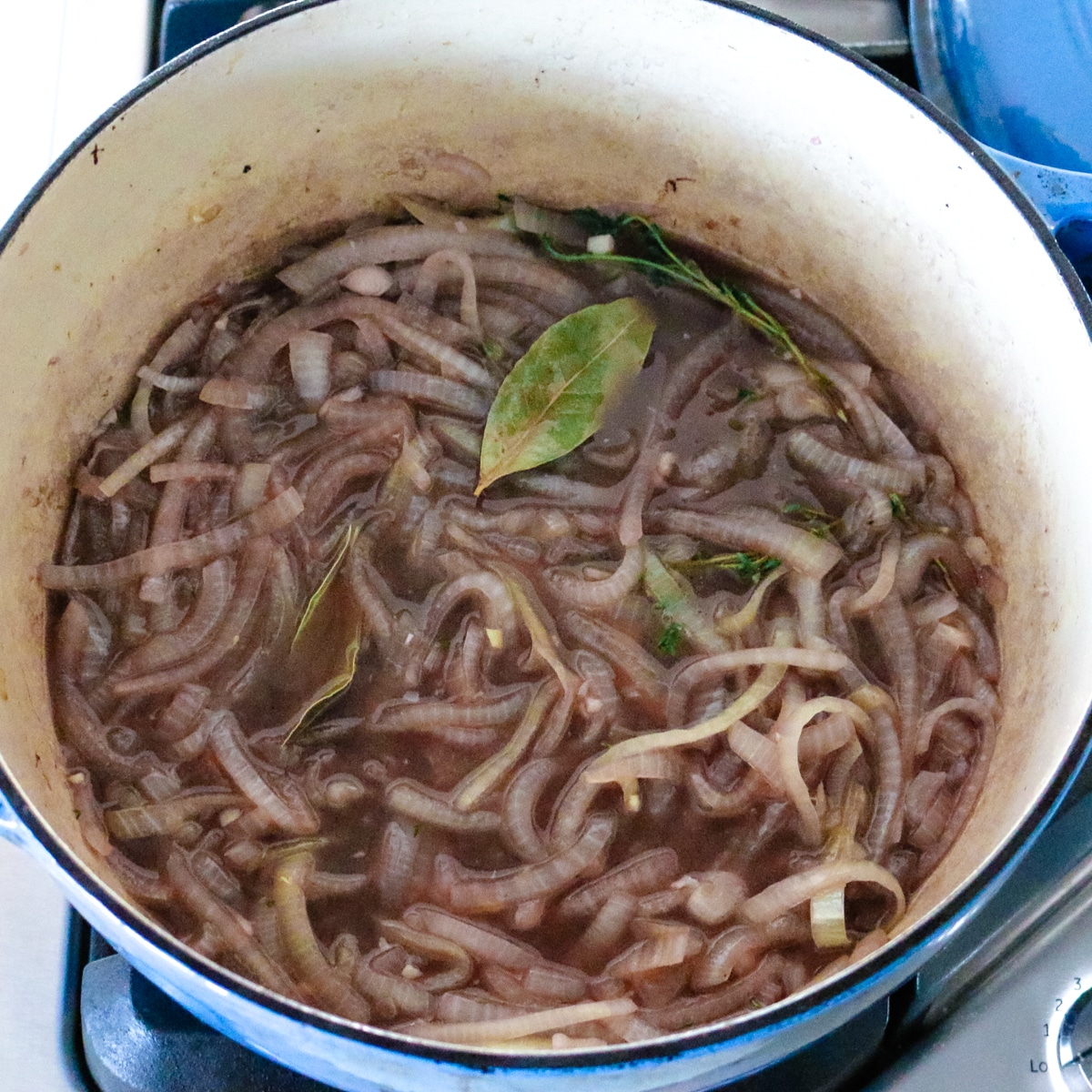 Simmering white onions and red wine in a pot.