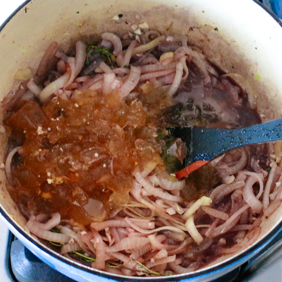 Adding aromatic ingredients to the pot with onions.