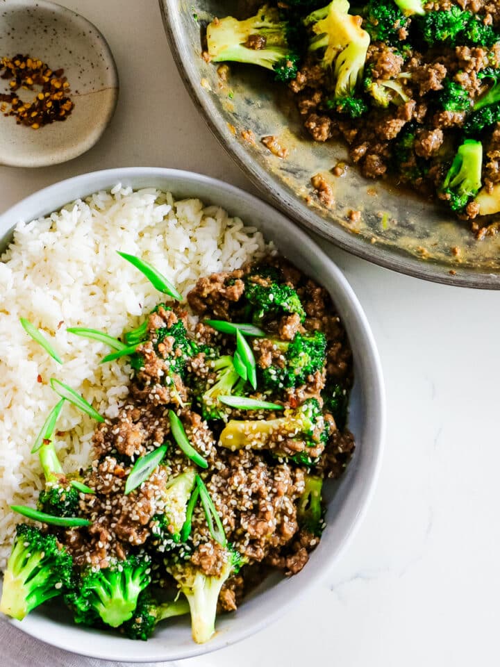 Ground beef with broccoli and rice on a plate, with extra ground beef, broccoli in a pan, and spices on the side.