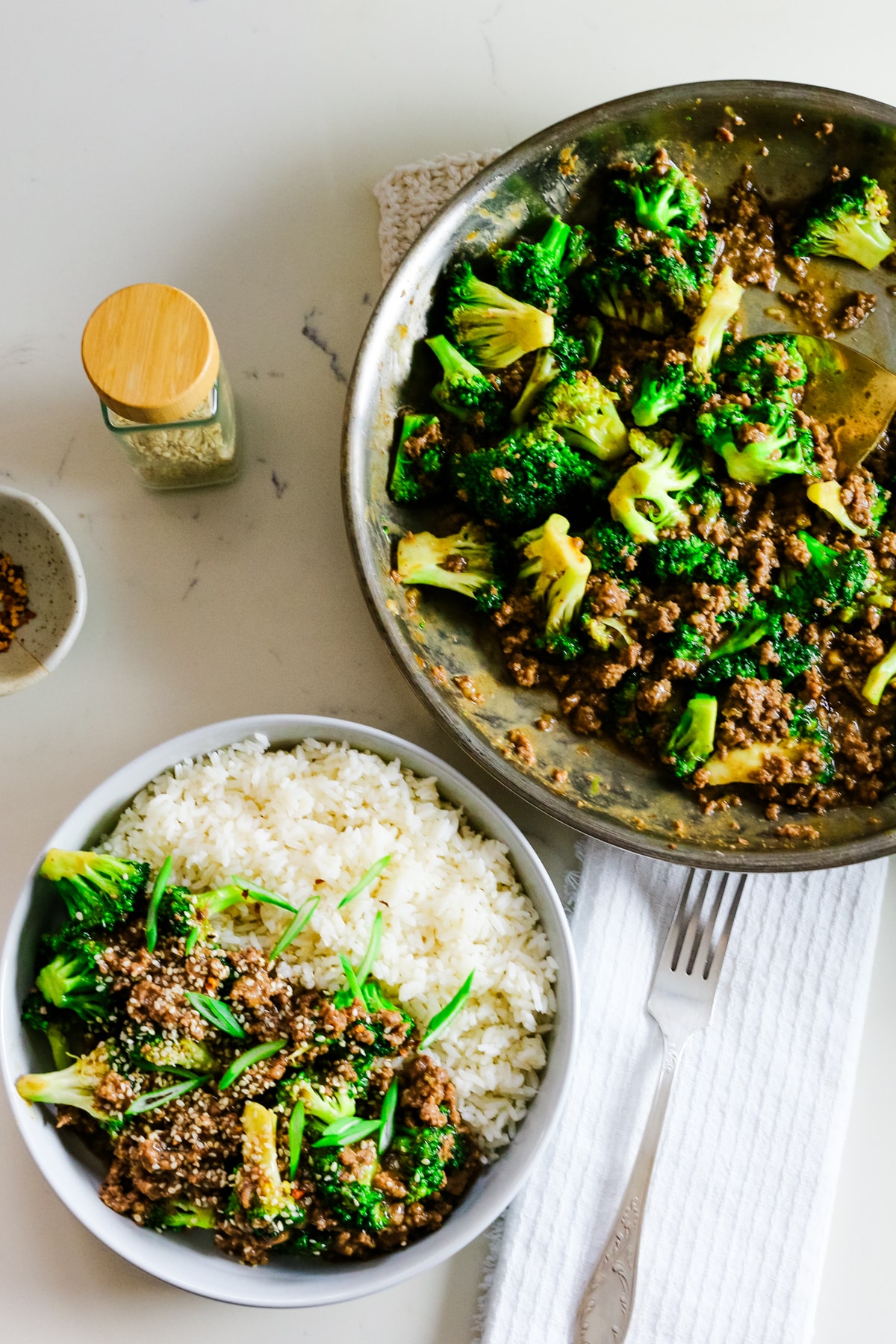 Ground beef with broccoli and rice on a plate, with extra ground beef and broccoli in a pan on the side.